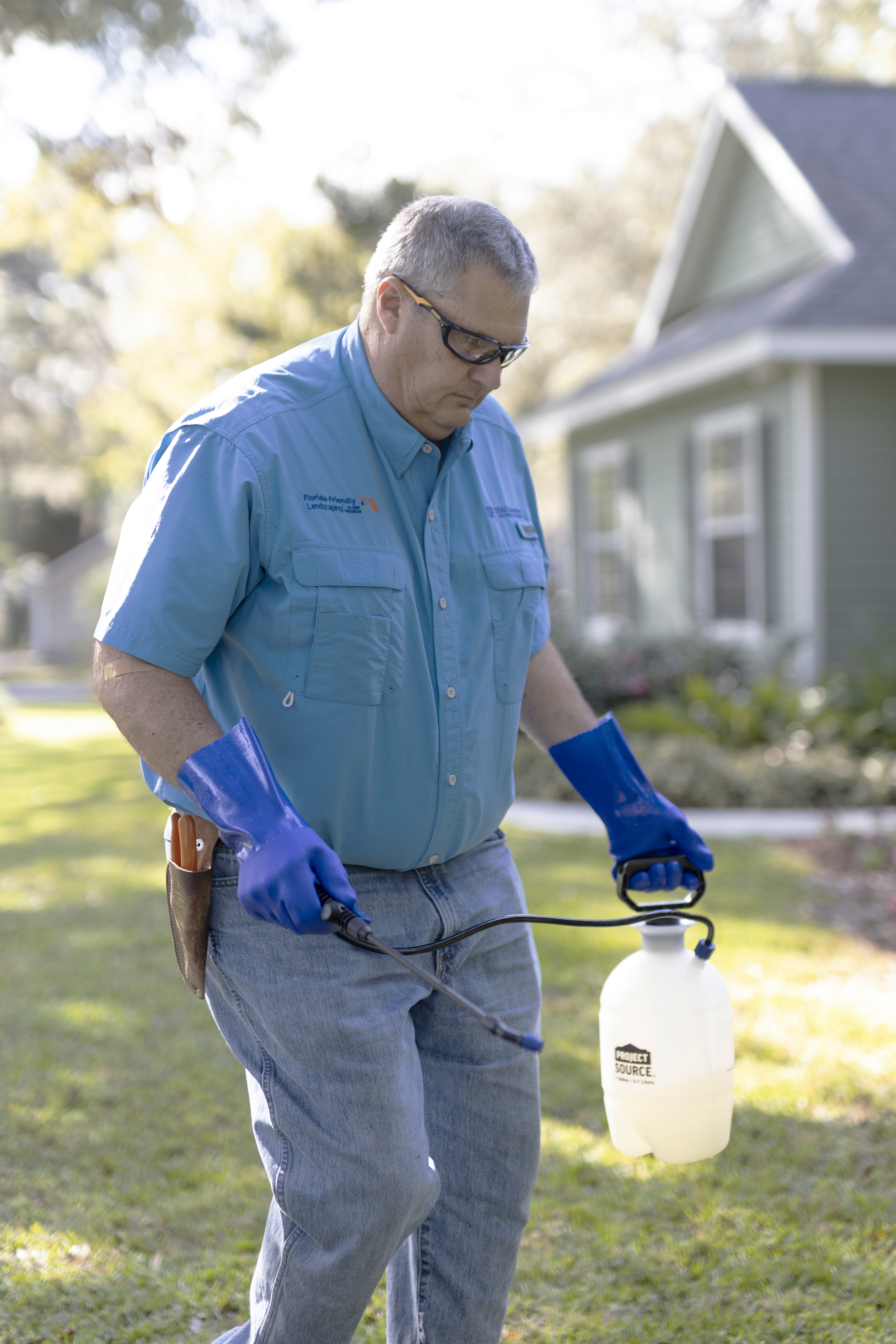 A man with gloves and PPE walking on a lawn.